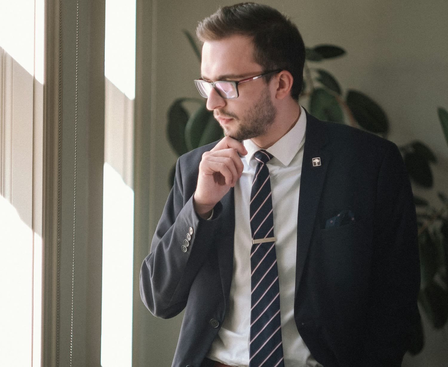 An attorney standing by an office window, thinking