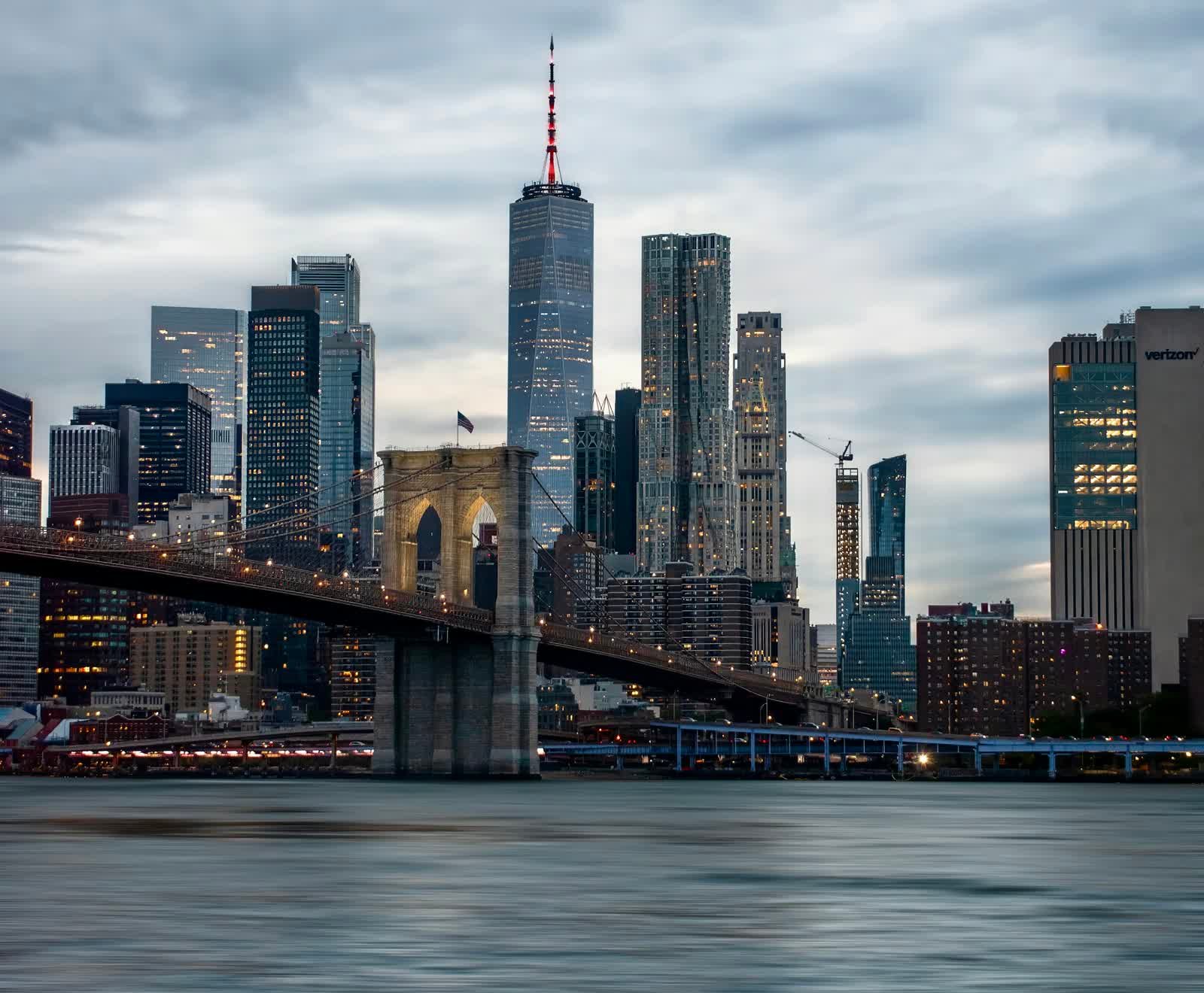 The Lower Manhattan skyline behind the Brooklyn Bridge at dusk