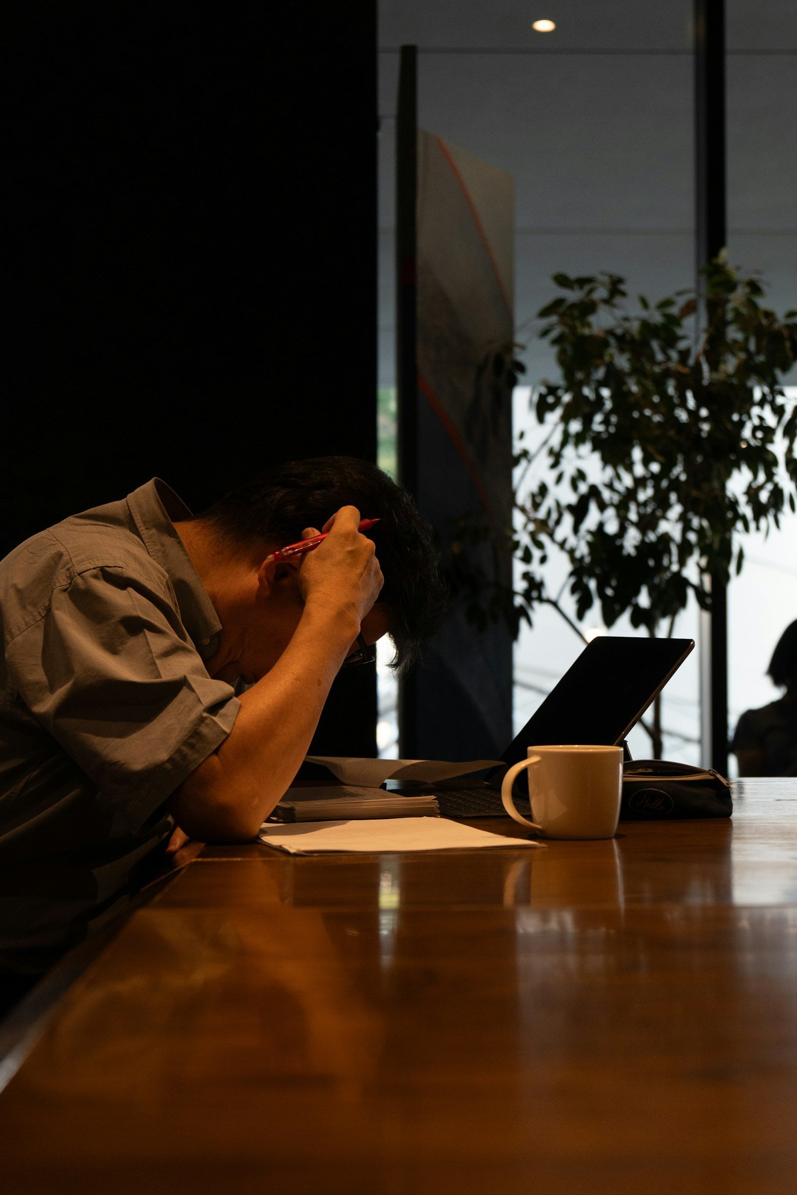 An attorney at a desk at night, head in his hands in front of a laptop